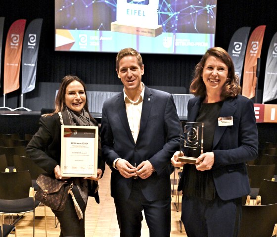 Marion Weber (li) und Andrea Hamacher nahmen den EIFLE Award 2024 von Markus Ramers, Präsident der Zukunftsinitiative, entgegen, © Eifel Tourismus GmbH Marion Weber (li) und Andrea Hamacher nahmen den EIFLE Award 2024 von Markus Ramers, Präsident der Zukunftsinitiative, entgegen, © Eifel Tourismus GmbH
