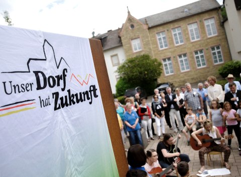 Bettingen im Bitburger Land ist mit aktuell 1.098 Einwohnern das gr&ouml;&szlig;te Dorf im Westen der Verbandsgemeinde mit Grundzentrumsfunktion. Der Ort verf&uuml;gt &uuml;ber eine sehr gute Infrastruktur: KiTA, Schule, Sportanlagen, B&uuml;rgerhalle, Jugendraum, Dienstleister, &Auml;rzte, Handel und Gewerbe, sowie Landwirtschaft und Gastronomie sind vorhanden. Im Ort besteht eine Pflegeeinrichtung mit 48 Pflegepl&auml;tzen. Leitsatz f&uuml;r Bettingen: Gute Infrastruktur erhalten und weiterentwickeln. Gemeinsam Altes bewahren und Neues wagen., &copy; BMEL/Photothek